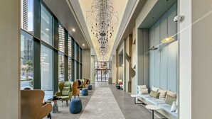 A spacious lobby with a central walkway, seating areas on both sides, and large windows offering views of the outside. - Skyline Escape 2 bedroom with Burj Khalifa View (Business Bay)