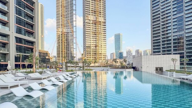 A modern hotel with a large pool, lounge chairs, and high-rise buildings in the background. - Skyline Escape 2 bedroom with Burj Khalifa View (Business Bay)