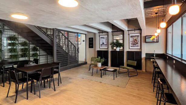 Ein modernes Interieur mit Holzboden, einer Treppe, einer Bar und Sitzgelegenheiten.