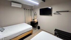Ein Schlafzimmer mit Bett, Nachttisch, Spiegel, Fernseher und einem kleinen Schreibtisch mit Stuhl.