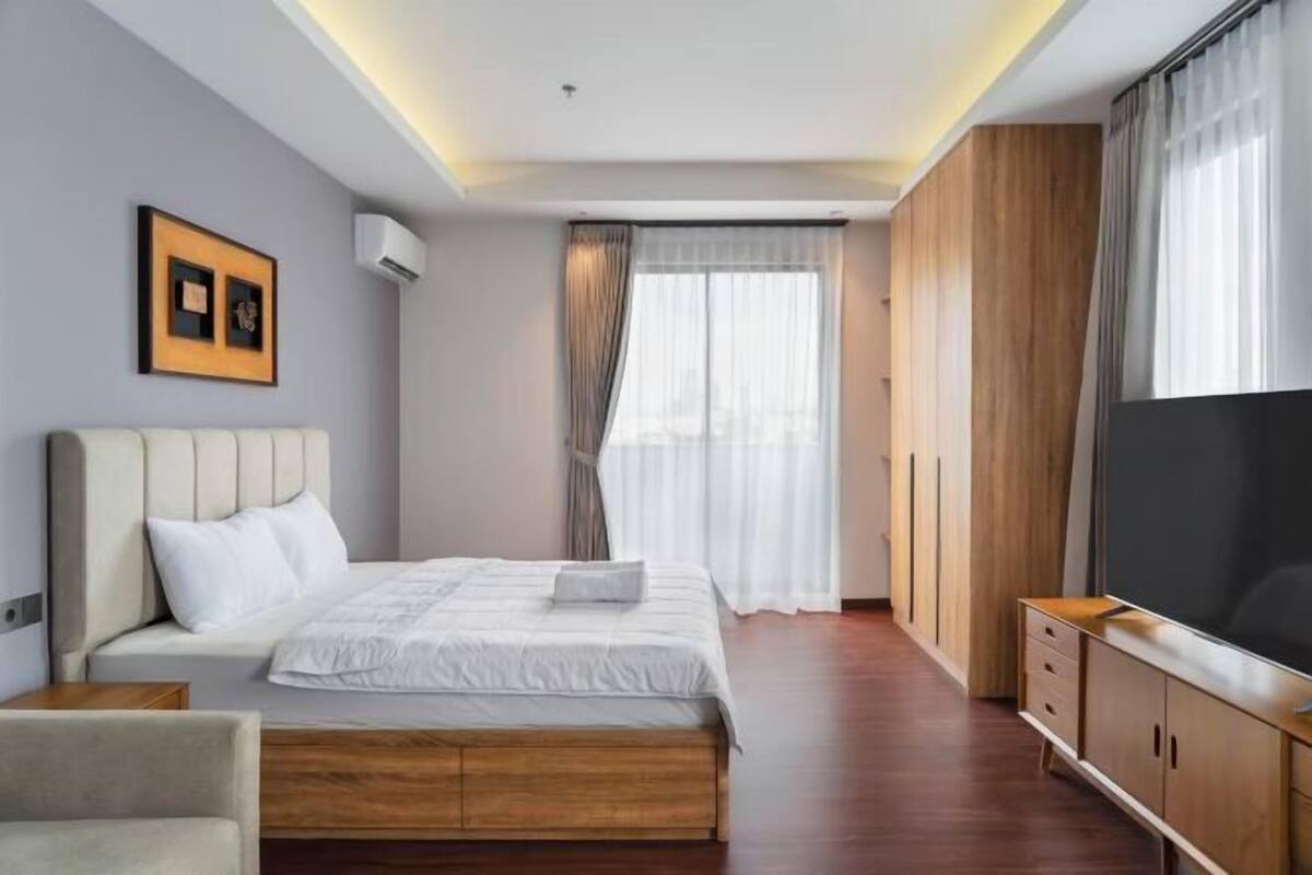 A modern bedroom with a bed, a TV, and a wardrobe.