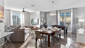 A spacious living room with a sofa, a dining table, and a kitchen area with a foosball table. - Modern 4BR Resort Townhome near Universal (Orlando)