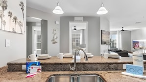 A modern kitchen with granite countertops, stainless steel sink, and pendant lighting. - Modern 4BR Resort Townhome near Universal (Orlando)