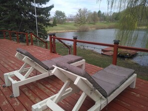 A deck with two white lounge chairs and a red railing overlooking a lake. - Lakeside Private suite (Queen bed room) (Loretto)