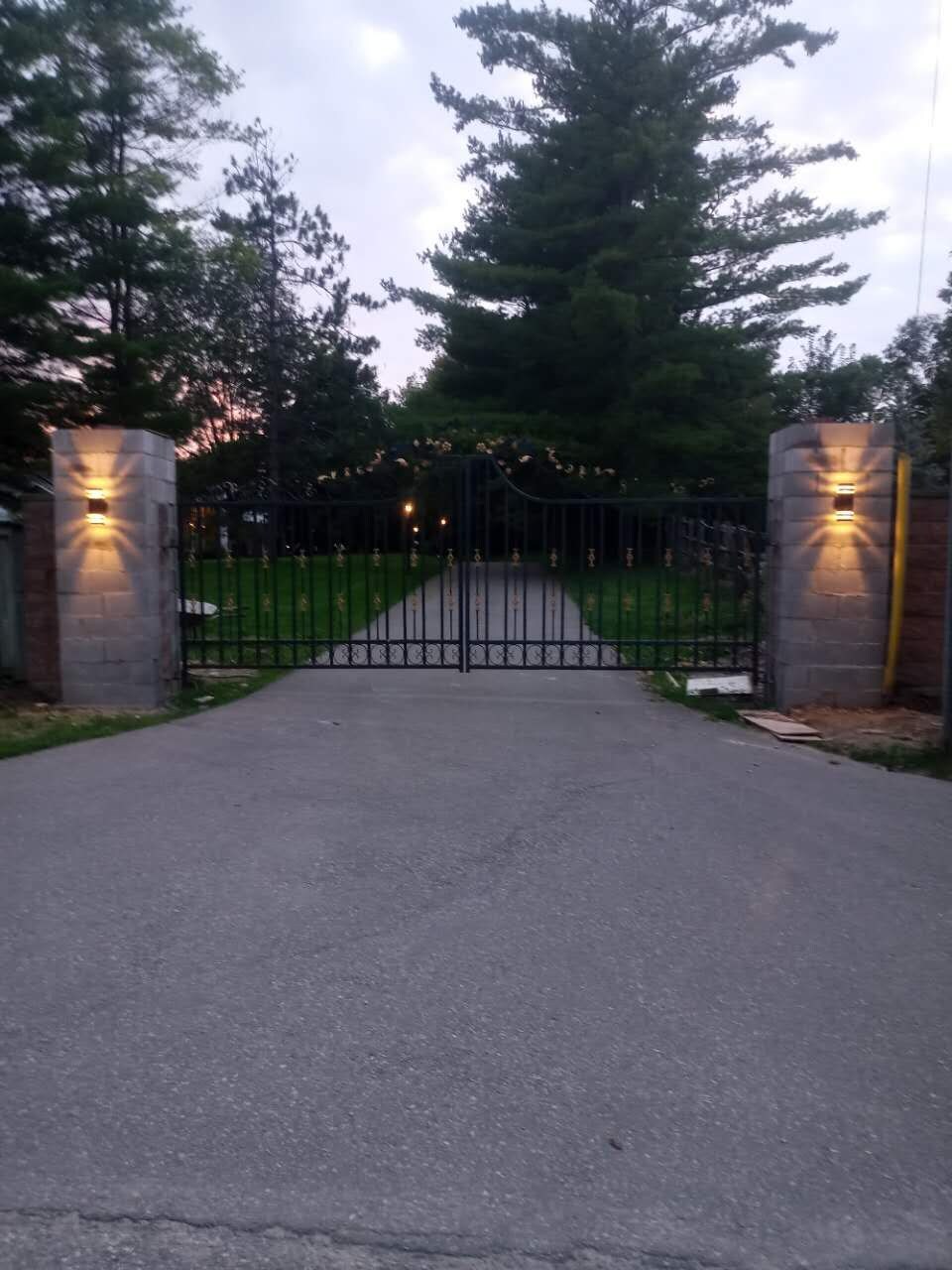 A gated driveway leading to a property with a paved path and a metal gate.