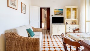 A room with a sofa, a dining table, a TV, and a cabinet. - Holiday Home 'Debby' with Private Terrace, Wi-Fi and Air Conditioning (Otranto)