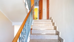 A staircase with a wooden handrail and a blue railing, leading to a room with a yellow wall and a hanging light fixture. - Holiday Home 'Debby' with Private Terrace, Wi-Fi and Air Conditioning (Otranto)