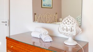 A hotel room with a glass-top dresser, a white lamp, and rolled towels on the dresser. - Holiday Home 'Debby' with Private Terrace, Wi-Fi and Air Conditioning (Otranto)