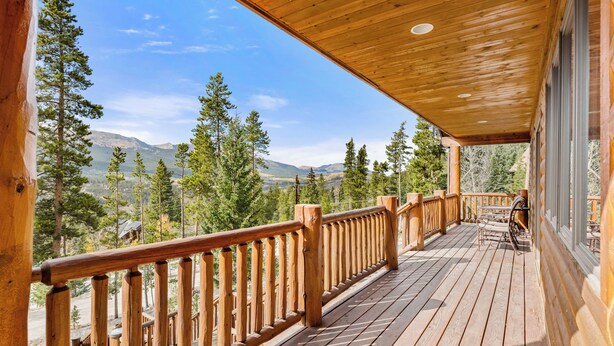 A wooden deck with a railing, overlooking a mountainous landscape. - Spacious House with Excellent Ski Area Views (Breckenridge)