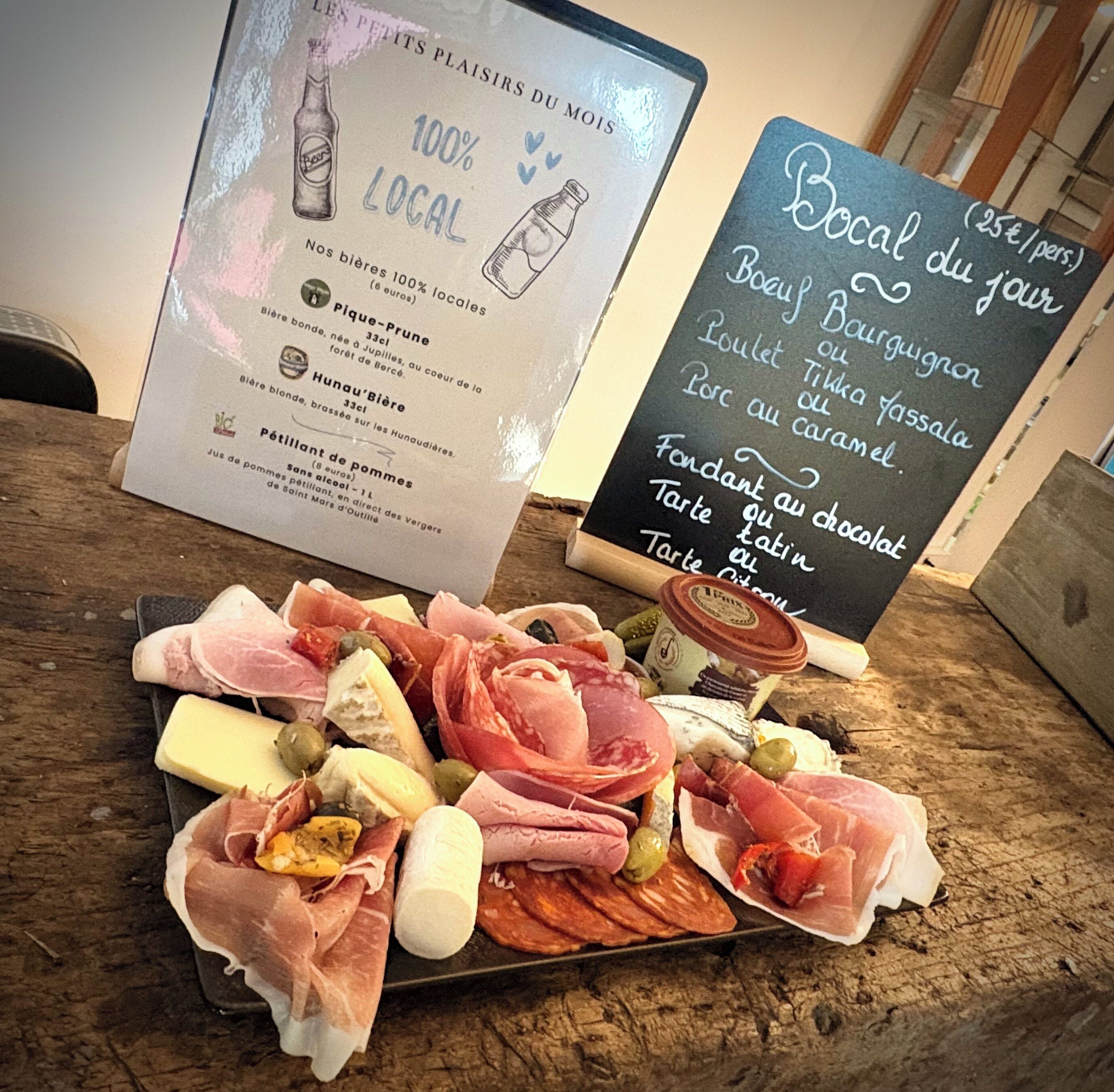 Une planche de charcuterie avec différentes sortes de viandes et de fromages, présentée sur une table en bois.