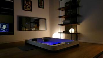 A modern room with a hot tub, a large mirror, and shelves with decorative items.