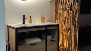 A modern bathroom with a wooden vanity, a large mirror, and a unique wooden wall feature. - Château de Posset - Les lofts (Teloché)
