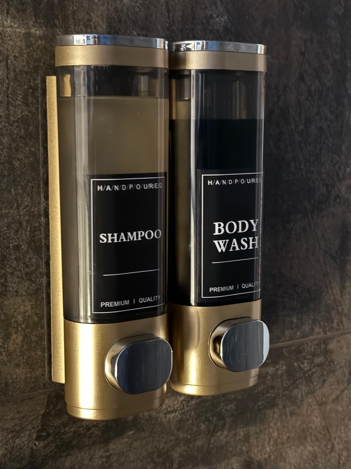 Two hand-poured shampoo and body wash dispensers mounted on a wall.