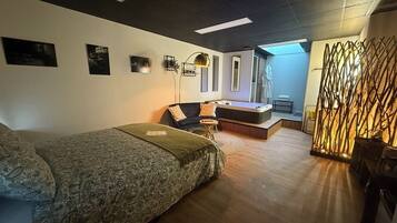 Une chambre moderne comprenant un lit, un canapé, une petite table et un élément de séparation décoratif.