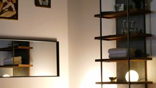 A modern bathroom with a built-in bathtub, wooden shelves, and artwork on the walls. - Château de Posset - Les lofts (Teloché)