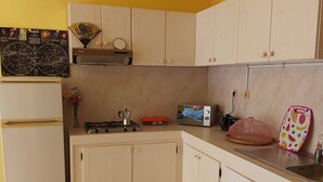 A compact kitchen with white cabinets, a gas stove, a refrigerator, and a small sink. - Gianni Apartment, Santa Maria, Sal, Cape Verde (Santa Maria)
