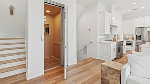 Eine moderne Küche mit weißen Schränken, Edelstahlgeräten und einer Holztreppe.
