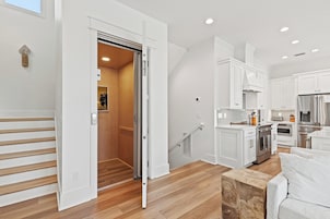 Una cocina moderna con armarios blancos, electrodomésticos de acero inoxidable y una escalera de madera.