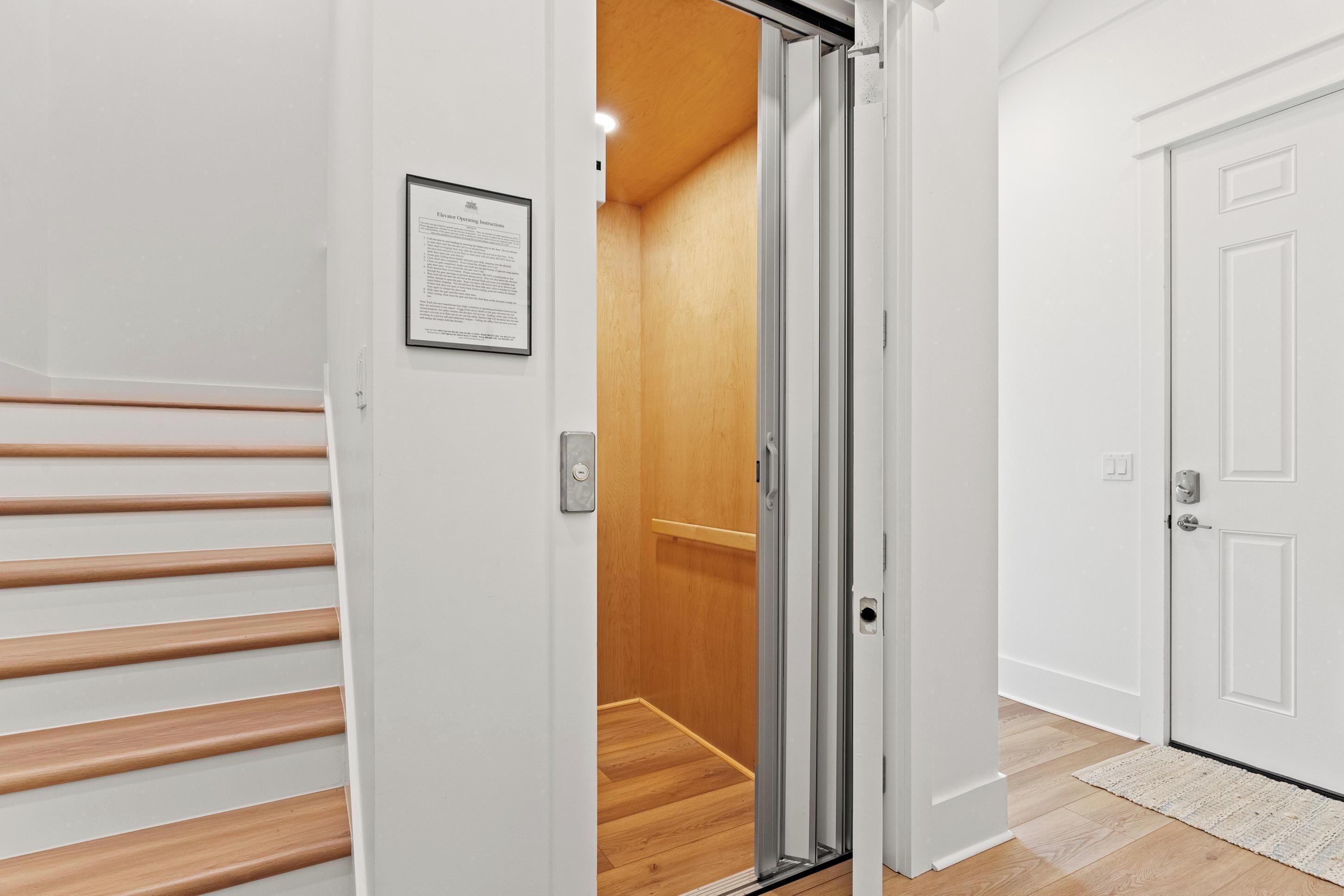 A modern interior with a wooden staircase, a sliding glass door leading to a room with wooden flooring, and a white door with a lock.