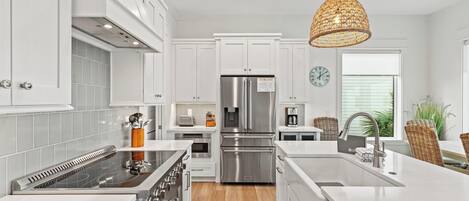 A modern kitchen with white cabinetry, stainless steel appliances, and a central island.