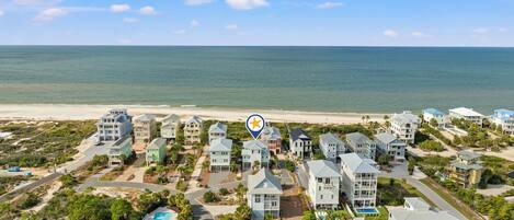 A coastal residential area with multiple two-story houses, a beach, and a clear sky.