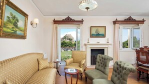 Una habitación con sofá, sillones, chimenea y vistas a una colina.