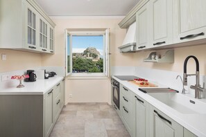 A modern kitchen with a view of a historic building through a window. - Nafsika's Grande Residence in Corfu Old Town (Kerkira)