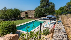 A swimming pool with lounge chairs, a stone building, and surrounding greenery. - Can Gallot De Punxuat – Mountain Views, Private Pool, Wi-Fi & Air Conditioning (Algaida)