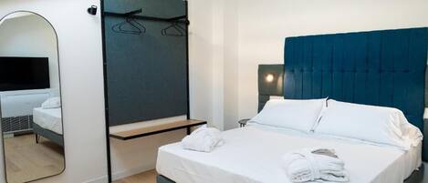 Et moderne hotelværelse med en stor seng, et sengebord, et spejl og en garderobe.
