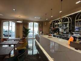 Un moderno bar con piso de mármol pulido, una barra con gran variedad de botellas y una zona de estar con mesas y sillas.