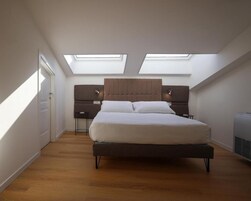 Une chambre à coucher avec un lit, deux tables de chevet, une tête de lit et des fenêtres de toit.