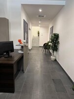 Zona de recepción con mostrador, computadora y una planta en maceta.