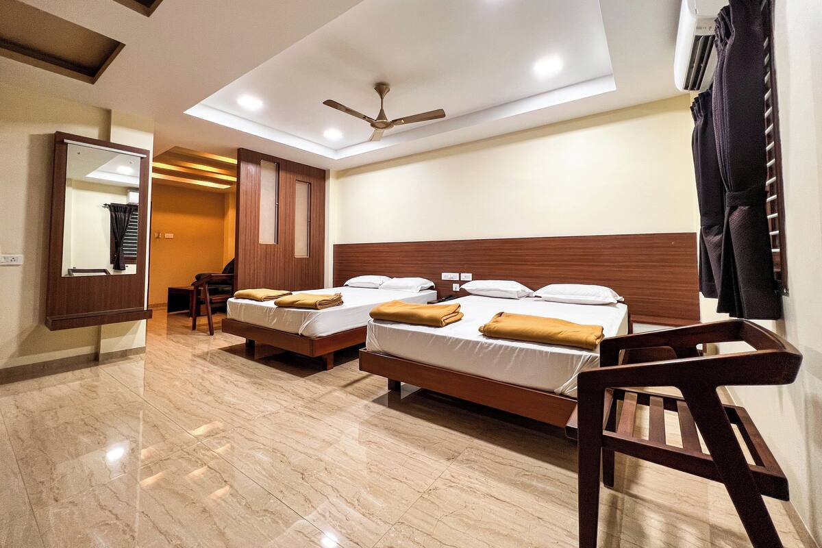 A hotel room with two beds, a ceiling fan, a mirror, a desk, and a chair.