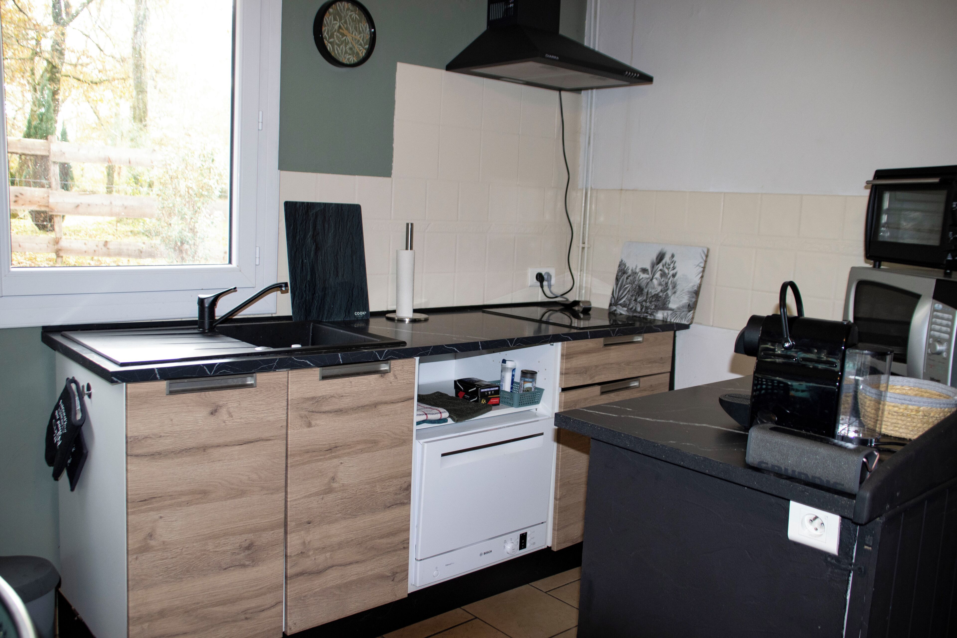 Cocina compacta con lavavajillas integrado, microondas y fregadero.