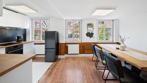 A modern kitchen with wooden countertops, a black refrigerator, and a dining area with a long wooden table and chairs. - Half-timbered apartment Calw - vacation in the picturesque and historic old town (Calw)