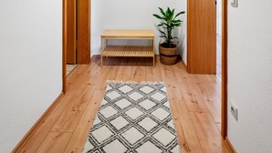 A hallway with wooden flooring, a bench, a hanging garment rack, a mirror, and a potted plant. - Half-timbered apartment Calw - vacation in the picturesque and historic old town (Calw)