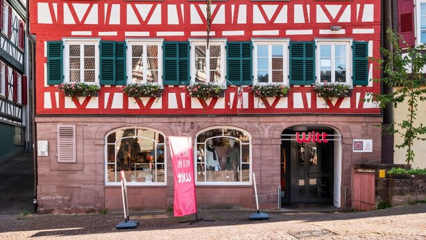 A traditional half-timbered building with a shop entrance, green shutters, and a sign that reads "Witt". - Half-timbered apartment Calw - vacation in the picturesque and historic old town (Calw)
