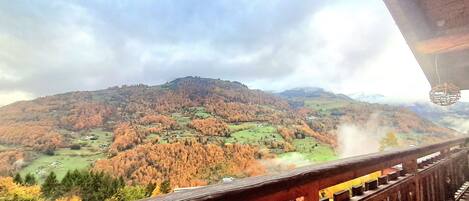 Paisaje montañoso con una vía de tren y una barandilla de madera.