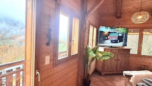 En træhytte med et stort vindue ud til en skovdal.