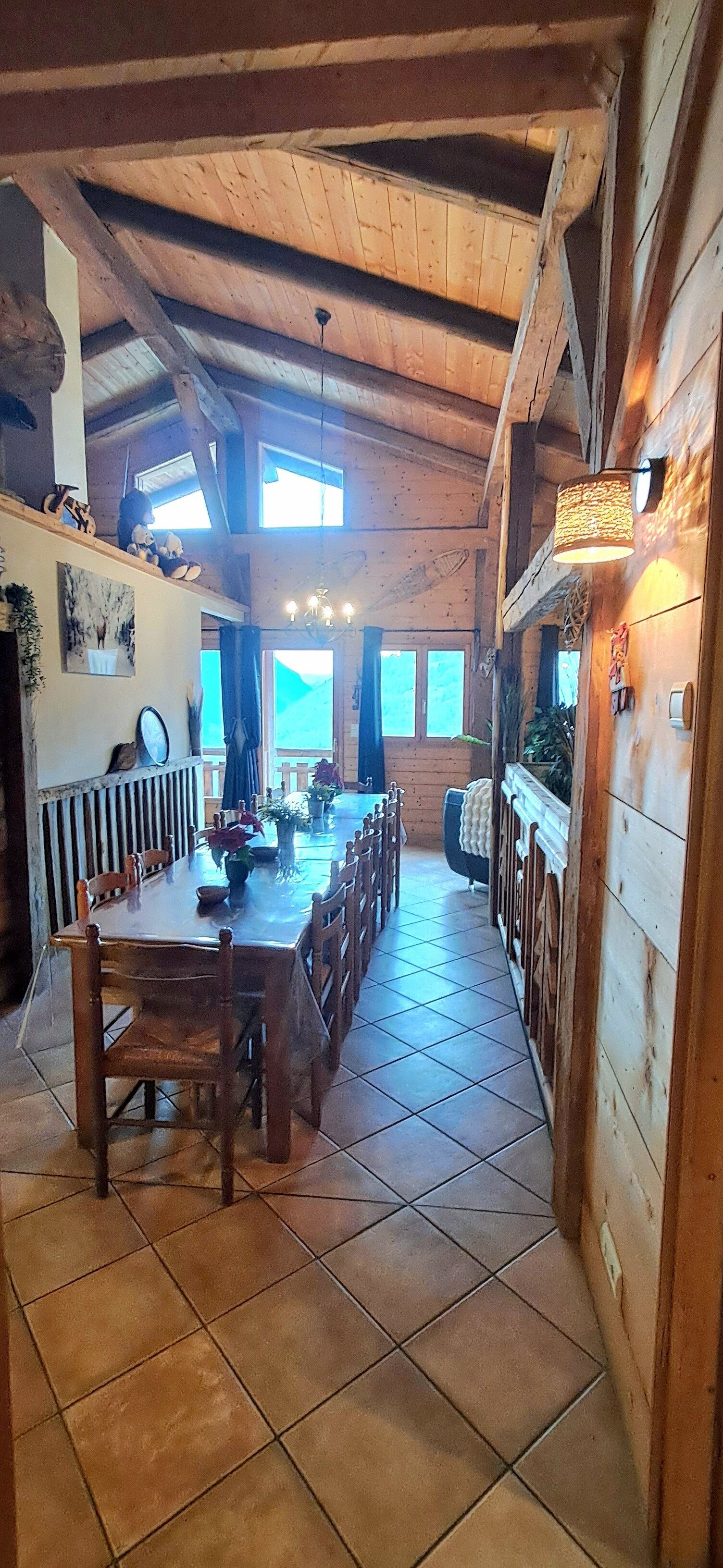 Un interior de madera con una larga mesa de comedor, sillas y una araña.
