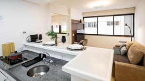 A modern kitchen with a granite countertop, stainless steel sink, and a built-in stove. There is a large window providing natural light and a view of the outside. - Lorena 1157 (São Paulo)