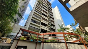 A high-rise building with multiple balconies, a metal structure in the foreground, and surrounding greenery. - Lorena 1157 (São Paulo)