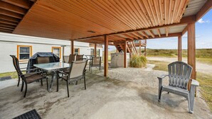 Una veranda esterna con zona salotto coperta, un tavolo e sedie.