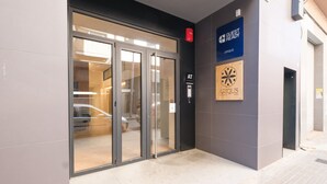 Een hotelentree met een glazen deur, een blauw bord waarop 'GUEST READY' staat, en een houten plaquette met de branding 'ARIUS'.