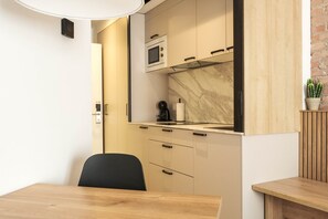 Une cuisine compacte équipée d’un four à micro-ondes encastré, d’une machine à café et d’une petite plante en pot.