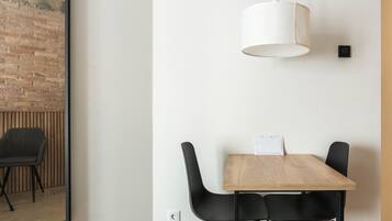 A modern dining area with a wooden table, black chairs, a white pendant light, and a brick wall.