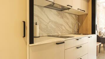 A modern kitchen with a marble backsplash, a stainless steel sink, and a black faucet.