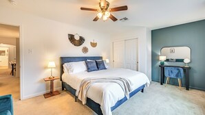 A bedroom with a bed, bedside table, lamp, and a ceiling fan.