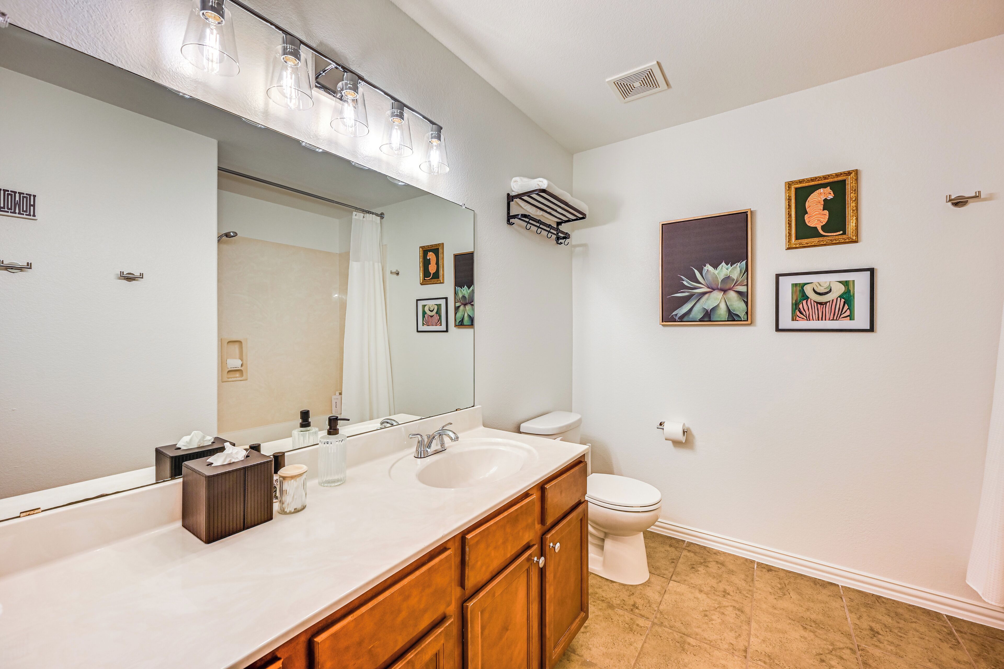A bathroom with a large mirror, a sink, a toilet, and a towel rack.