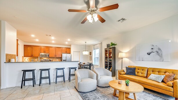 A modern kitchen with a central island, bar stools, and a dining area with a sofa and coffee table.
